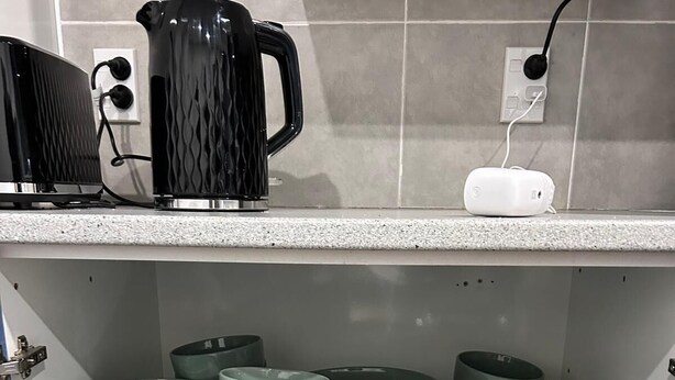 En kökshylla med staplade tallrikar, skålar och köksredskap.