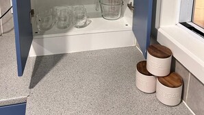 Ett köksskåp med hyllor där olika typer av glas, muggar och måttkoppar förvaras.