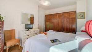 A bedroom with a bed, a television on a dresser, a wardrobe, a chair, and a bedside table. - Appartamento Residenza Chiara: Sunny Balcony and Mountain View, Laveno Mombello, Italy (Laveno Mombello)