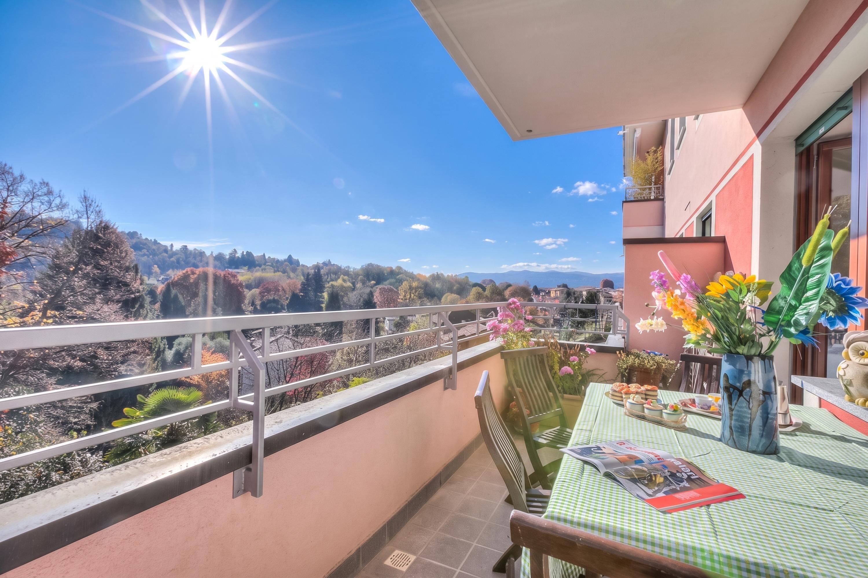A balcony with a table set for dining, a chair, and a vase of flowers.