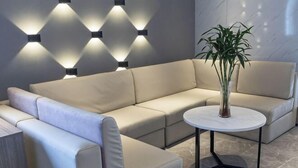 A modern living room with a beige sectional sofa, a round coffee table, and a potted plant. - 7 Days Premium Hotel (Beijing Qinghe Yongtaizhuang Metro Station) (Beijing)