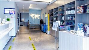A modern hotel lobby with a reception desk, a world map on the wall, and shelves stocked with toiletries. - 7 Days Premium Hotel (Beijing Qinghe Yongtaizhuang Metro Station) (Beijing)