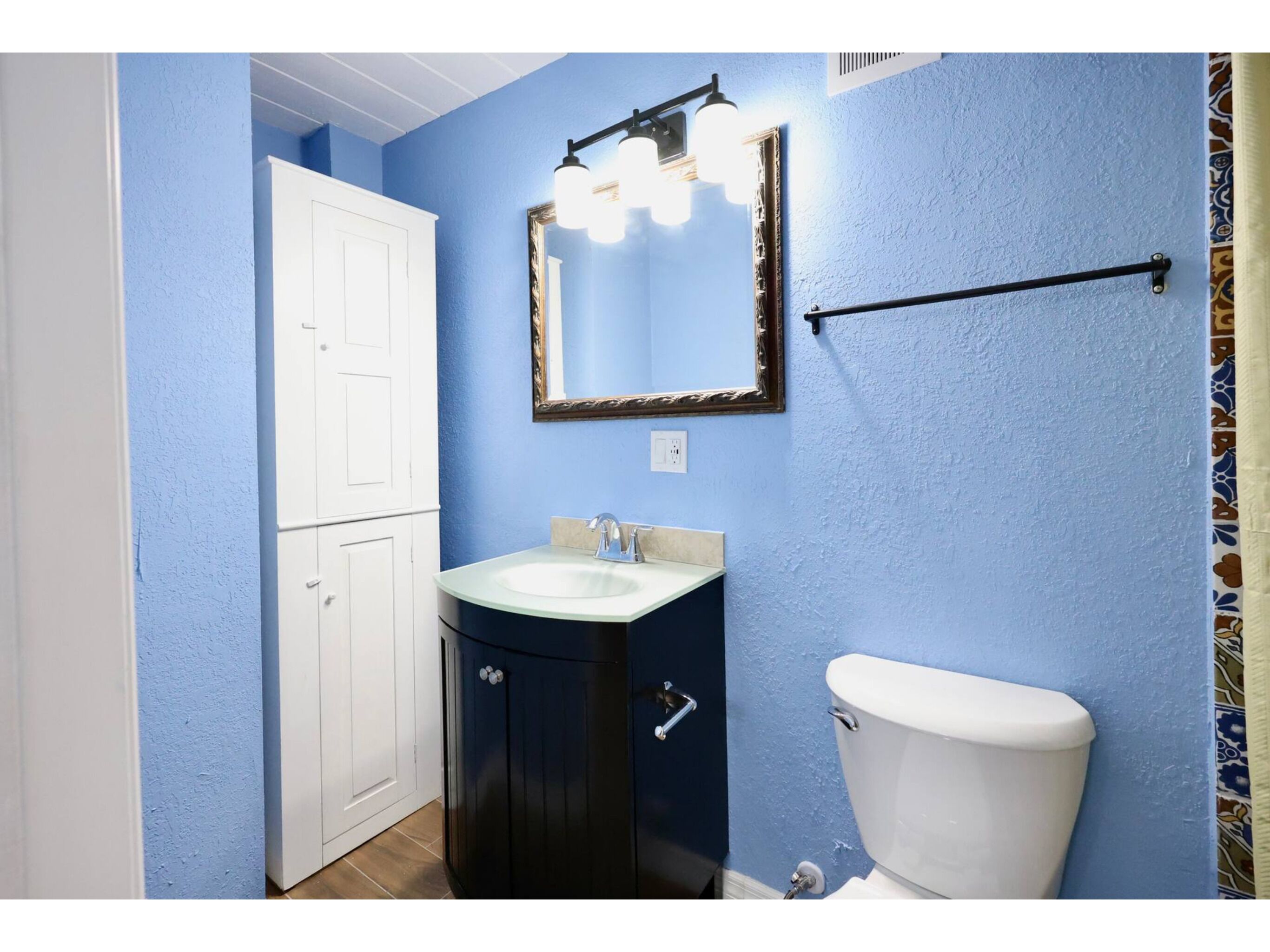 Ein Badezimmer mit Toilette, Waschbecken mit Spiegel und Handtuchhalter.