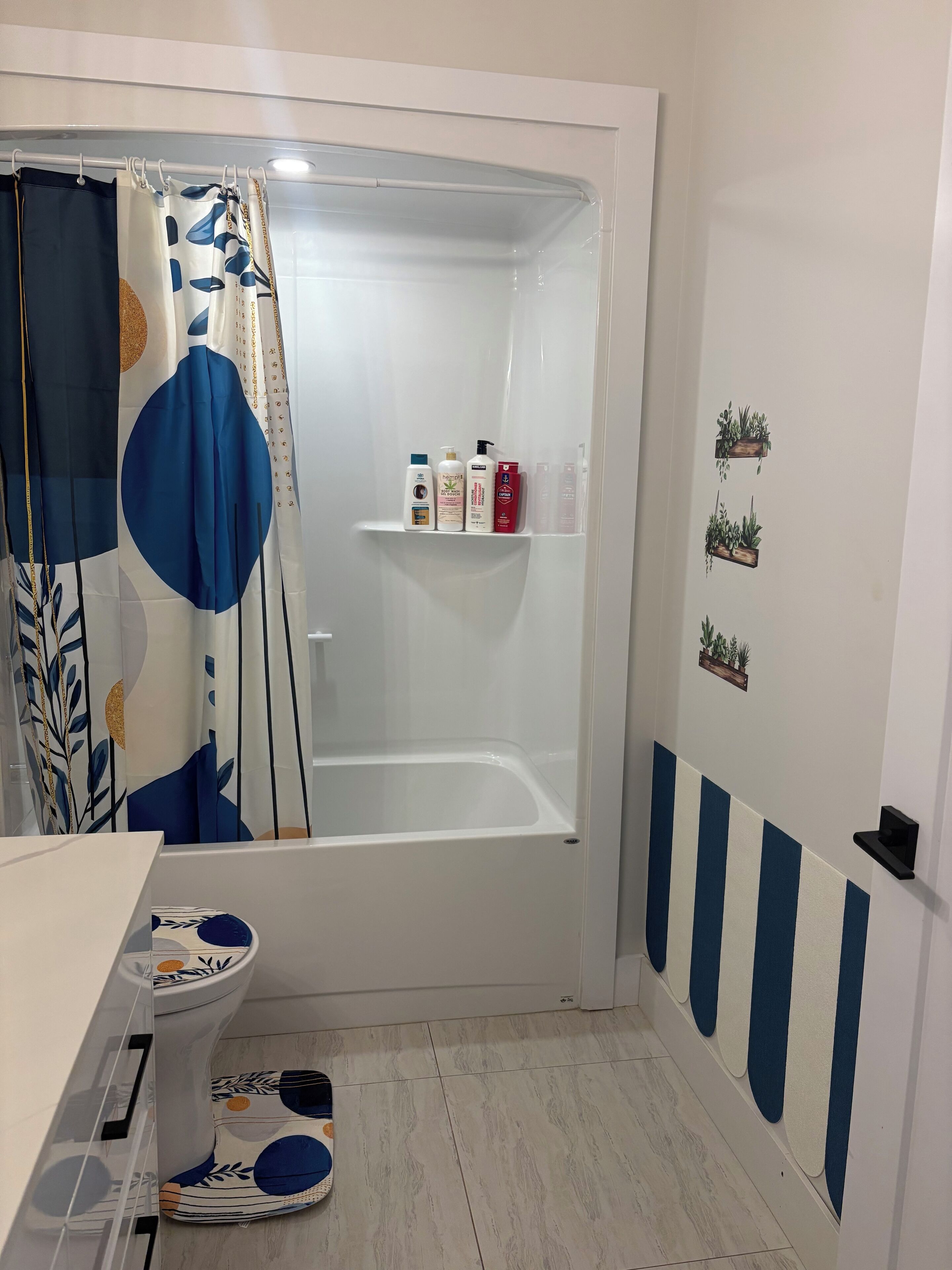 A bathroom with a shower, toilet, and a shelf with toiletries.