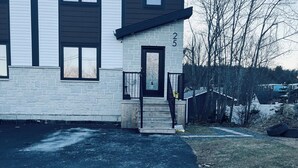 A two-story house with a stone facade, a black door, and a number '25' on the wall. - The Cozy Haven (Halifax)