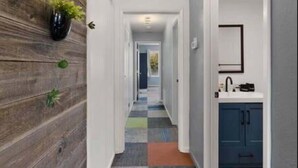 A hallway with a wooden wall, a colorful carpet, and a blue cabinet with a sink. - Blue&Gold Art Deco 2BR1BA Loft close to Genentech (South San Francisco)