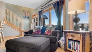 A cozy living room with a sofa, ottoman, and a bookshelf. - Tempest Ridge Townhouse 34 (Newry)