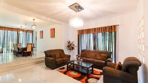 A spacious living room with a large sofa set, a coffee table, and a chandelier. - Ravo Residence (Galle)