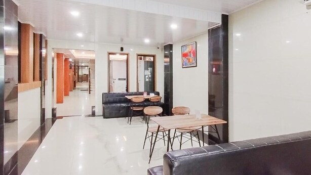 Una hall d'albergo moderna con un divano in pelle nera, tavoli in legno e un divano nero.