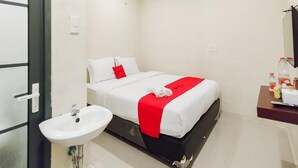 Una camera d'albergo con un letto, un comodino, un lavandino e uno specchio.