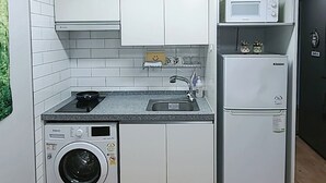 A compact kitchen with a washing machine, a microwave, and a refrigerator. - Incheon Airport ANN Guesthouse (Incheon)
