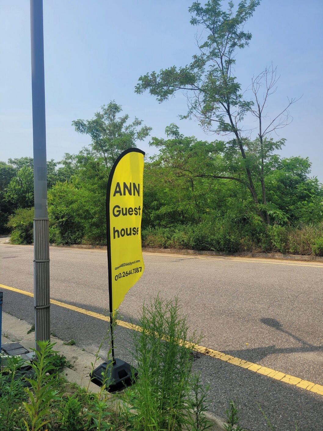 Een gele vlag met de tekst 'ANN Guest house' en contactgegevens.