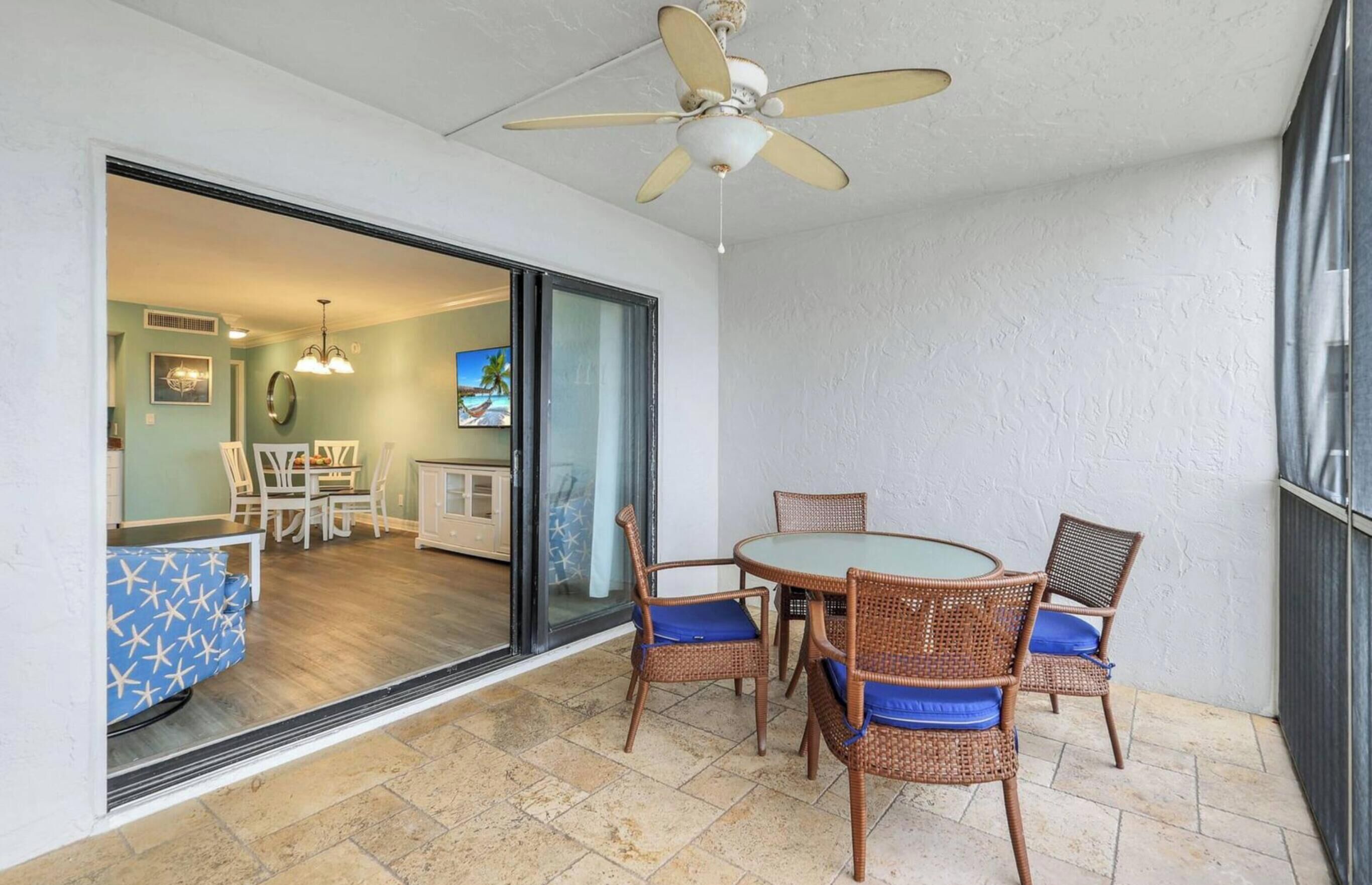 Un patio con mobiliario de mimbre, un ventilador de techo y vistas al área de estar.
