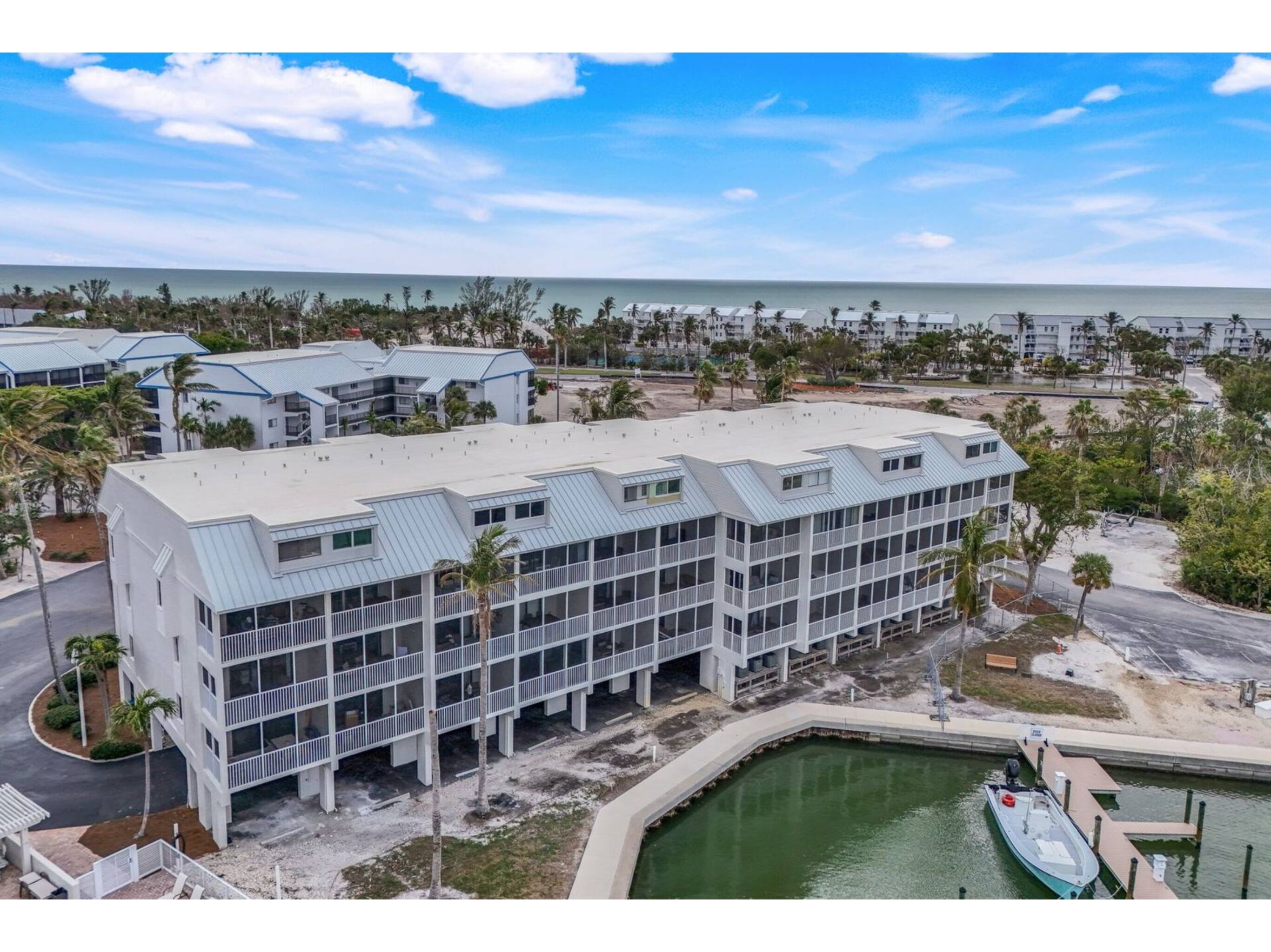 A modern hotel with multiple floors, a marina, and a beach view.