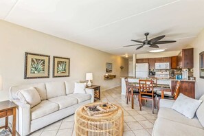 A living room with a sofa, a coffee table, and a dining area with chairs and a table. - Partial oceanview 1 bedroom condo, AC, across from beach, near shops & dining (Kihei)