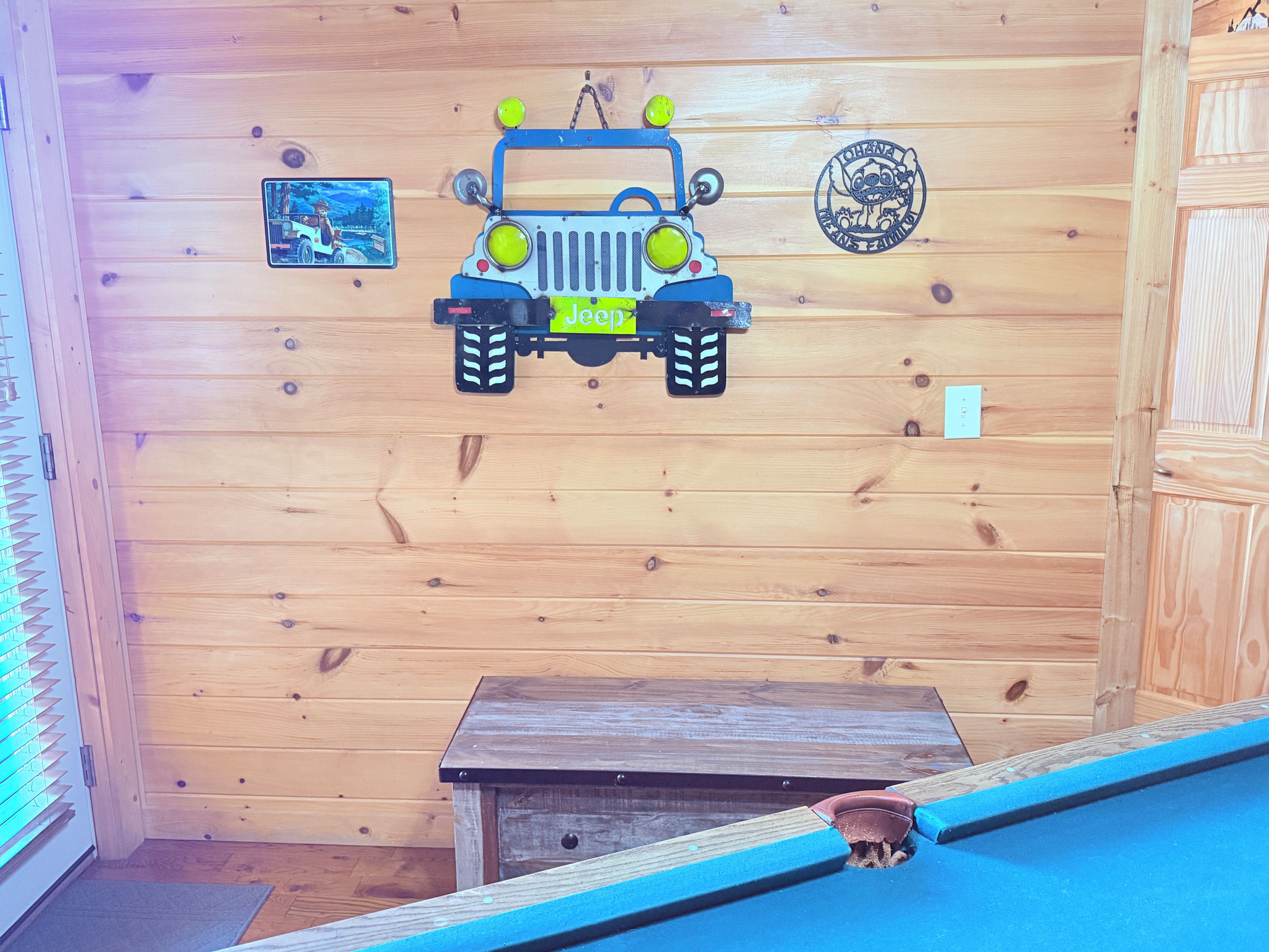A wooden interior with a Jeep decal, a small table, and a framed picture on the wall.