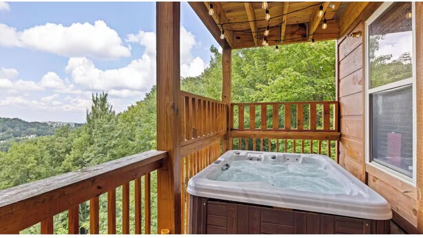 Terraza de madera con jacuzzi y vista a un paisaje boscoso.