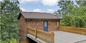 A small wooden cabin with a blue door, a star decoration, and a wooden fence. - Romantic Getaway + Hot Tub + Views (Gatlinburg)