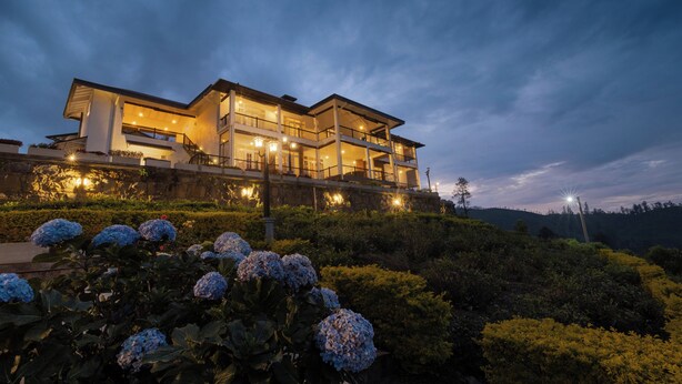 A modern two-story house with multiple balconies and a well-lit exterior. - Ruvinya Hills Luxury Bungalow (Lindula)