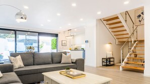Ein modernes Wohnzimmer mit einem grauen Sofa, einem Couchtisch und einer Treppe mit Holzboden.