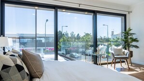 Ein modernes Schlafzimmer mit einem großen Bett, einer Glastrennwand und Blick ins Freie.