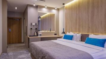 A modern hotel room with a large bed, a bedside table, a mirror, and a wooden headboard.
