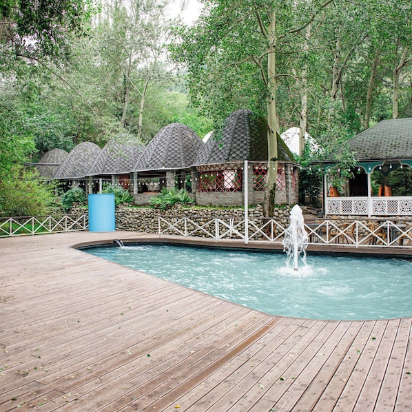 A wooden deck with a pool and a water fountain.