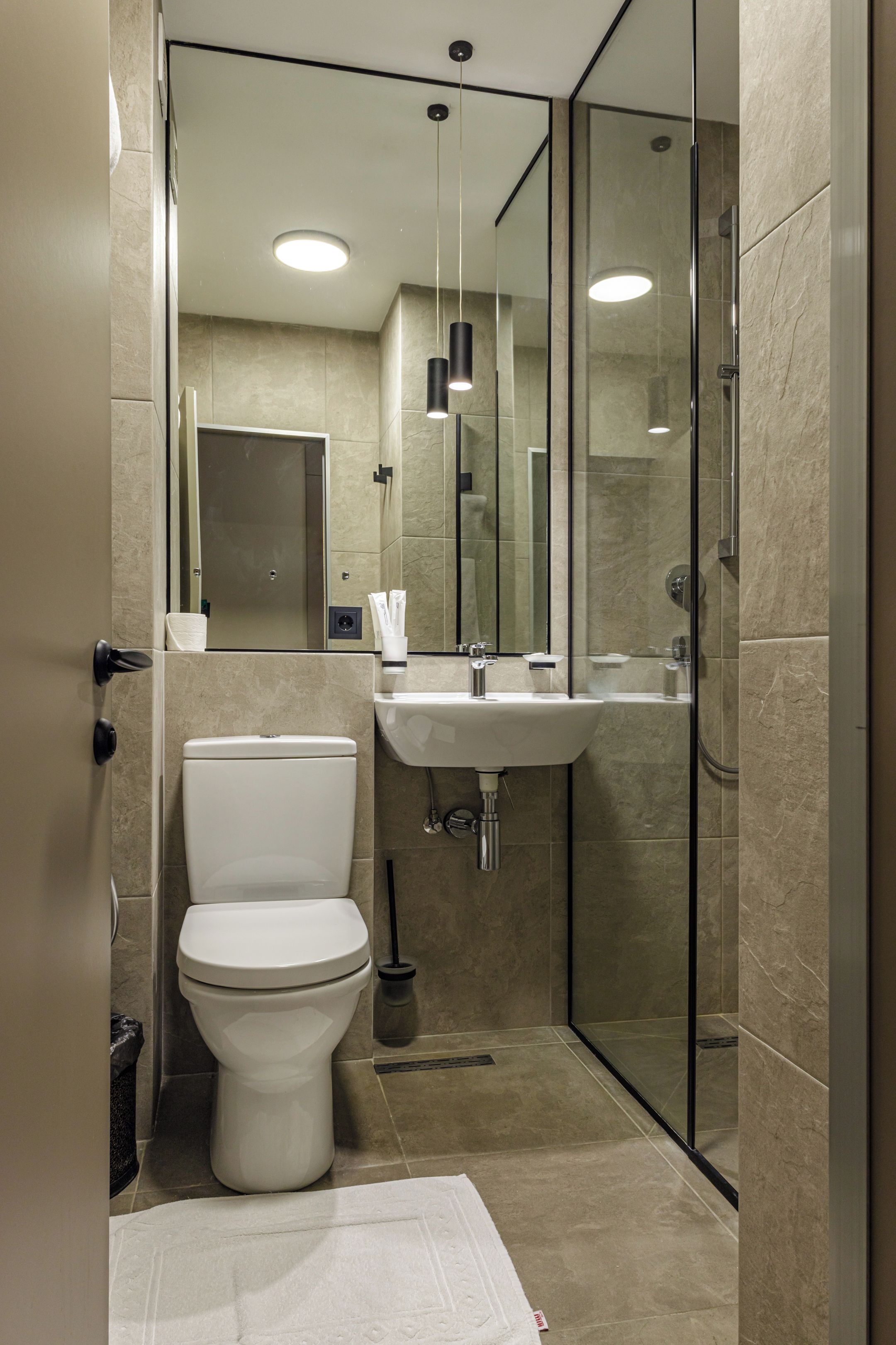 A modern bathroom with a toilet, sink, and glass shower enclosure.