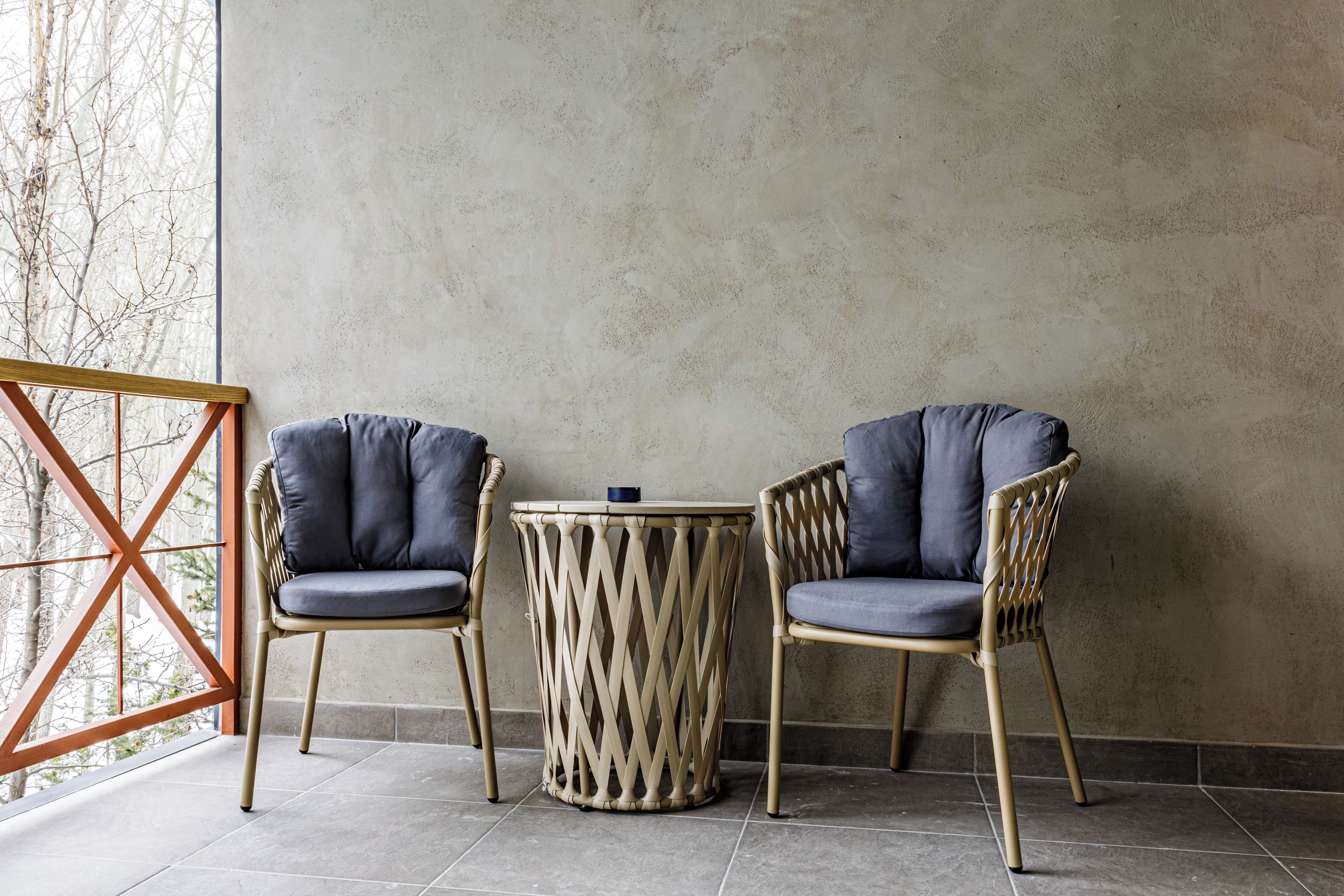 Two chairs with cushions, a round table, and a wooden floor.