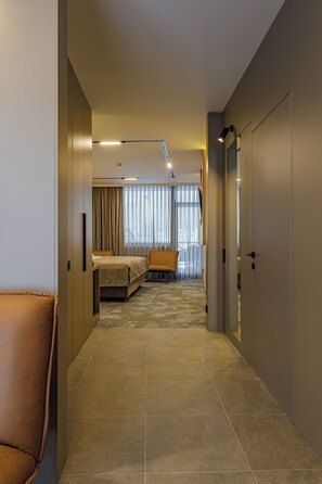 A modern hotel room with a bed, a seating area, and a large window with curtains. - TAU-House (Almaty)