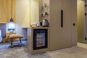 Una kitchenette compacta con refrigerador, cafetera y una pequeña encimera.