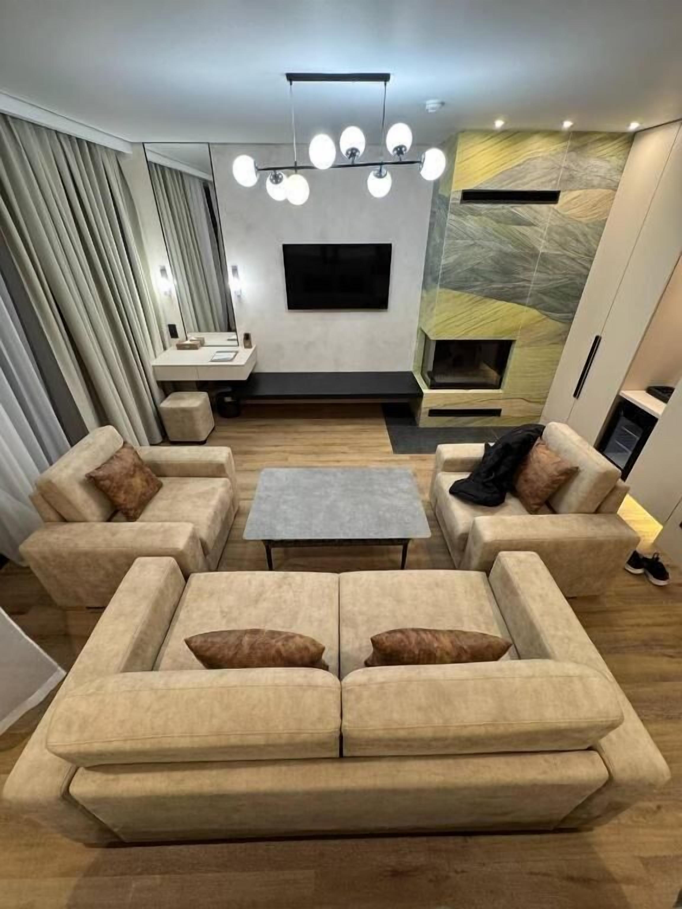 A modern living room with a sofa set, a coffee table, and a TV mounted on the wall.