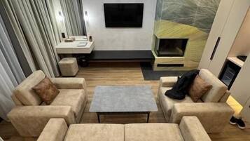 A modern living room with a sofa set, a coffee table, and a TV mounted on the wall.