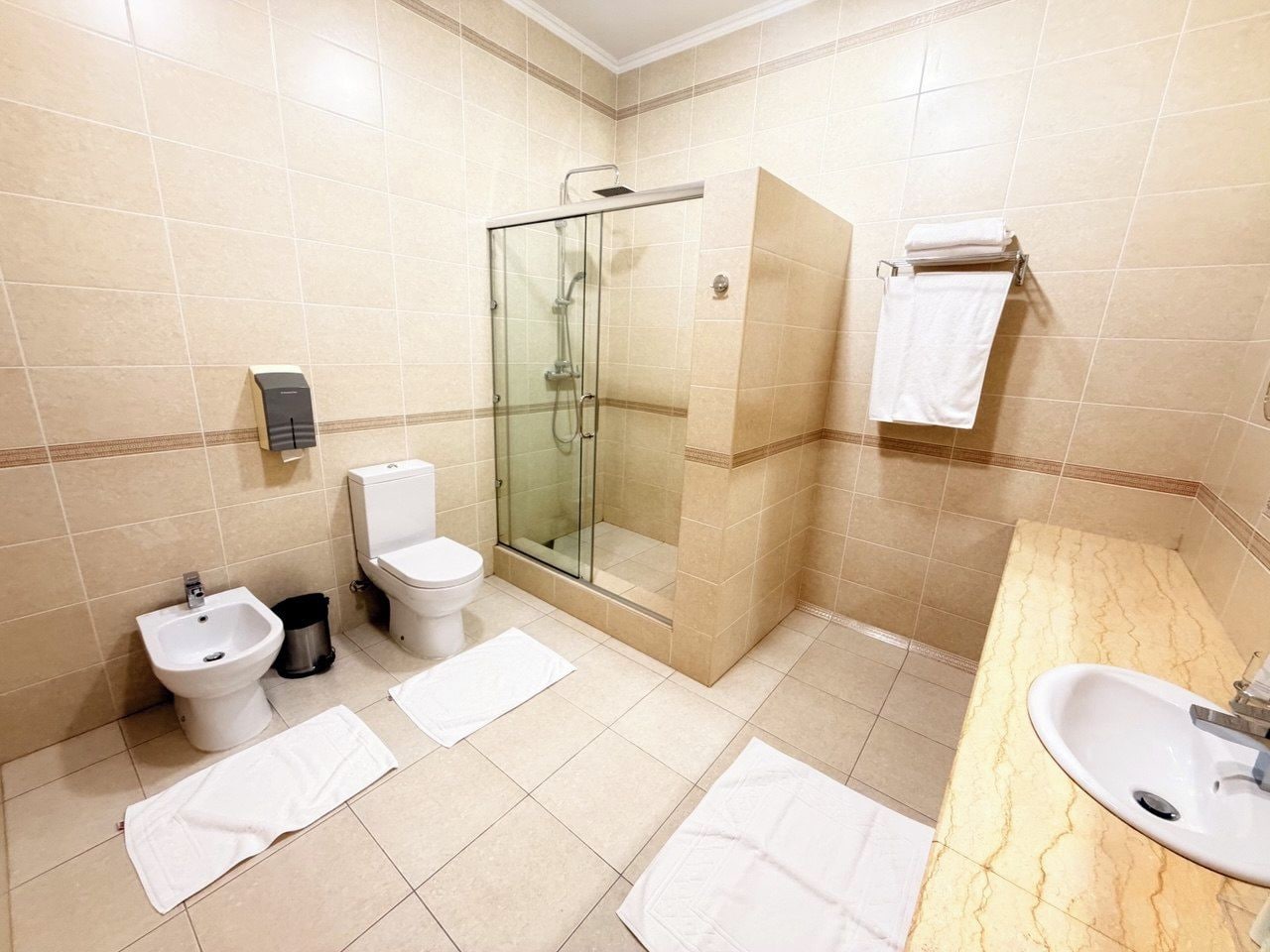 A bathroom with a glass-enclosed shower, a bidet, a toilet, and a sink.