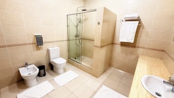 A bathroom with a glass-enclosed shower, a bidet, a toilet, and a sink.