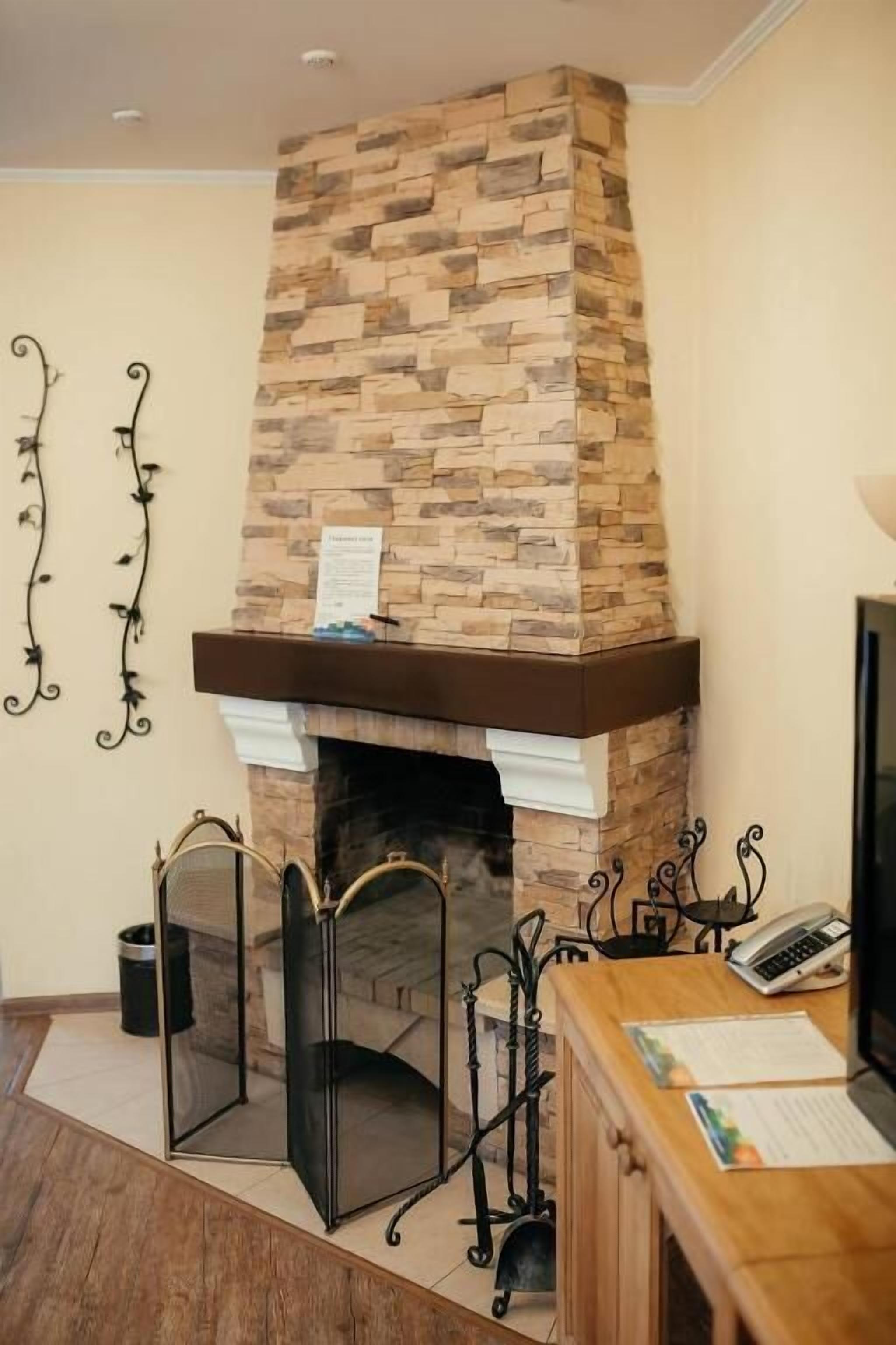 A room with a stone fireplace, a wooden desk, and a trash can.
