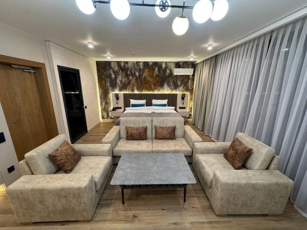 Una habitación de hotel moderna con un conjunto de sofá, una mesita y una cama con cabecera.