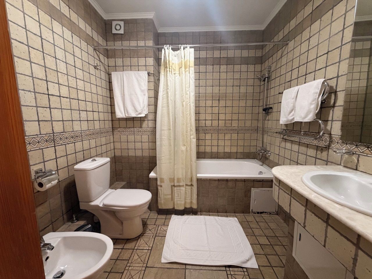 Un baño con inodoro, bidé, bañera y lavamanos.