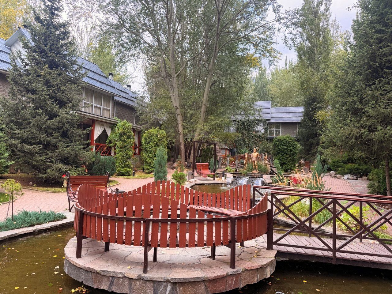 A garden with a wooden bench, a small pond, and a bridge.