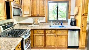 A kitchen with wooden cabinets, a stove, a microwave, a sink, and a dishwasher.