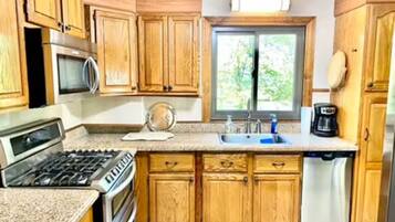 A kitchen with wooden cabinets, a stove, a microwave, a sink, and a dishwasher.