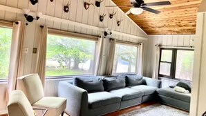 A cozy living room with a sectional sofa, a chair, and a ceiling fan.