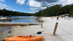 A sandy beach with a dock, a small boat, and a lifeguard tower.