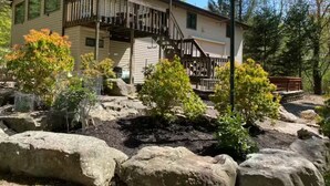 A two-story house with a wooden deck and a stone pathway.