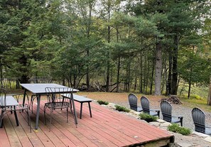 A deck with outdoor seating and a view of a forested area.