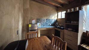 Una cocina rústica con una mesa de madera, un refrigerador, una estufa y una ventana con vistas.