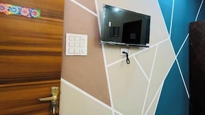 Une pièce dotée d’une porte en bois, d’un téléviseur fixé au mur, d’une prise de courant et d’un sol carrelé.