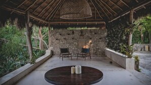 Un espacio al aire libre cubierto con una pared de piedra, una mesa redonda con velas y sillas.