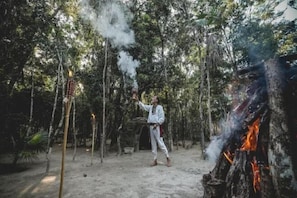 A person in a forest clearing with a fire and smoke rising. - Wakax Hacienda - Cenote & Boutique Hotel (Tulum)