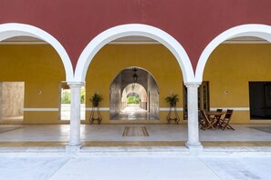 Une cour intérieure abritée par des arcades, avec un chemin central et des espaces de repos en plein air.